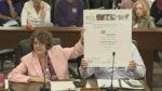 Maureen holding up a poster while speaking.