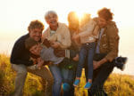 Generations at play in sunshine on a grassy hill.