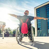 man in a wheel chair in an open public space with arms outstretched.